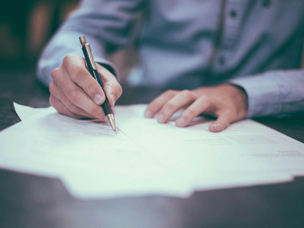 A person reviewing and signing paperwork at a desk